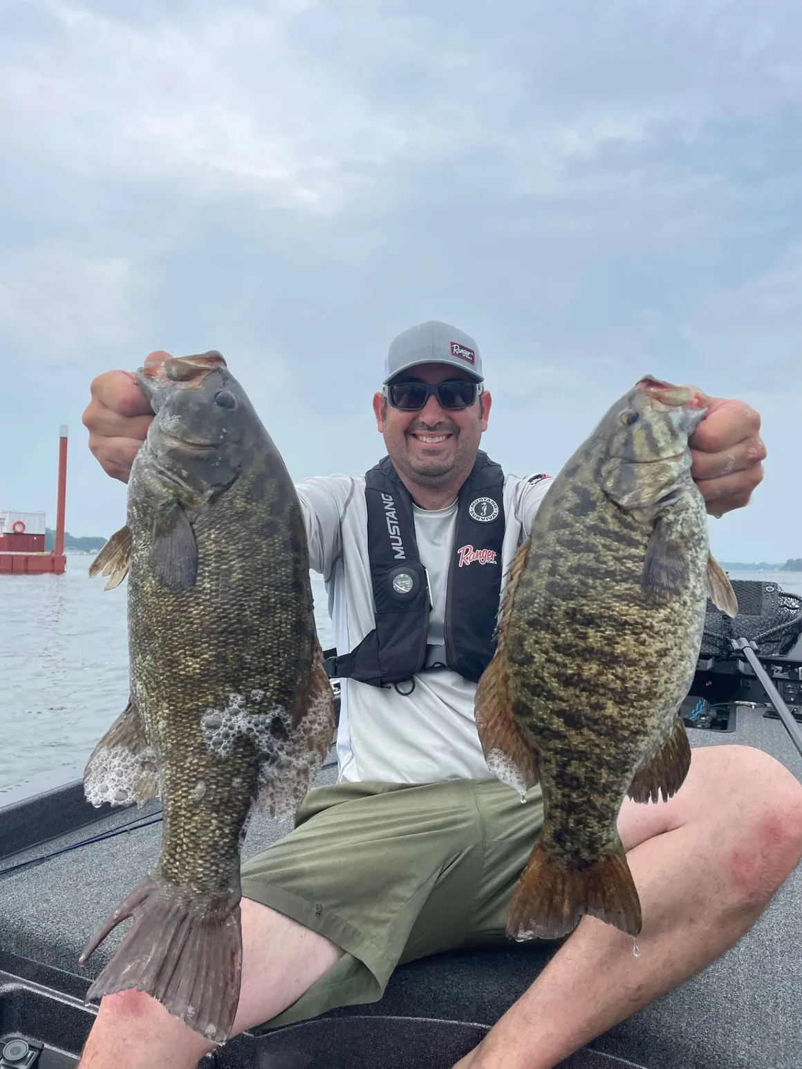 Big JP holding two giant smallmouth bass on the water